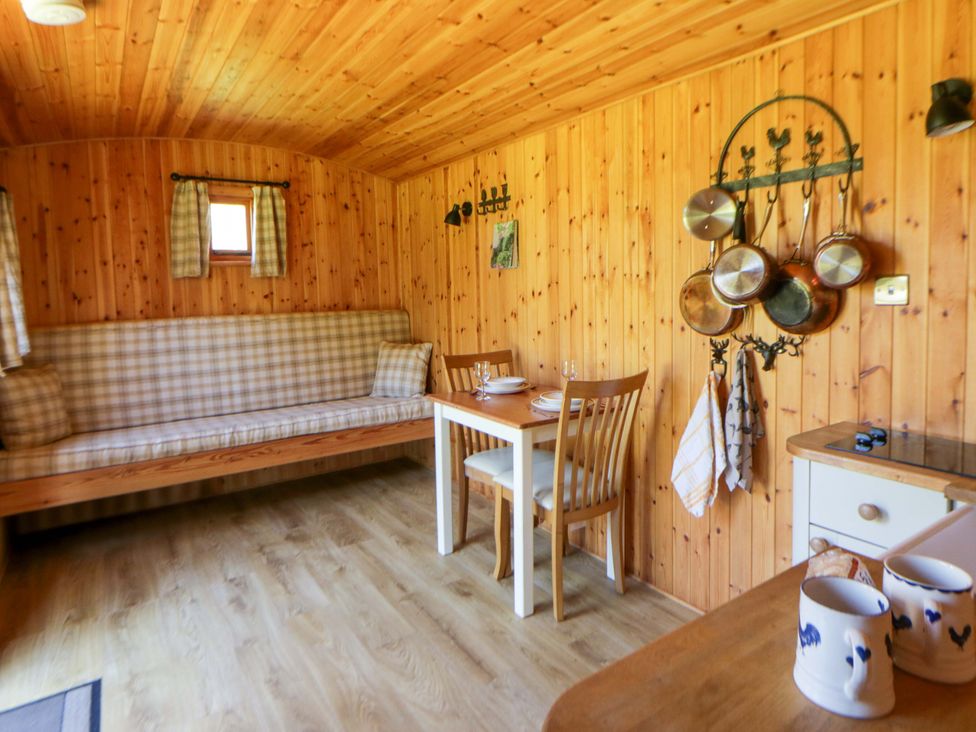 A snug area with a dining table and seating at Bill’s Shepherds Hut near Talgarth