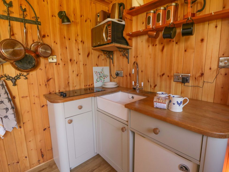A kitchen with cabinets, sink, and cooking utensils at Bill’s Shepherds Hut near Talgarth