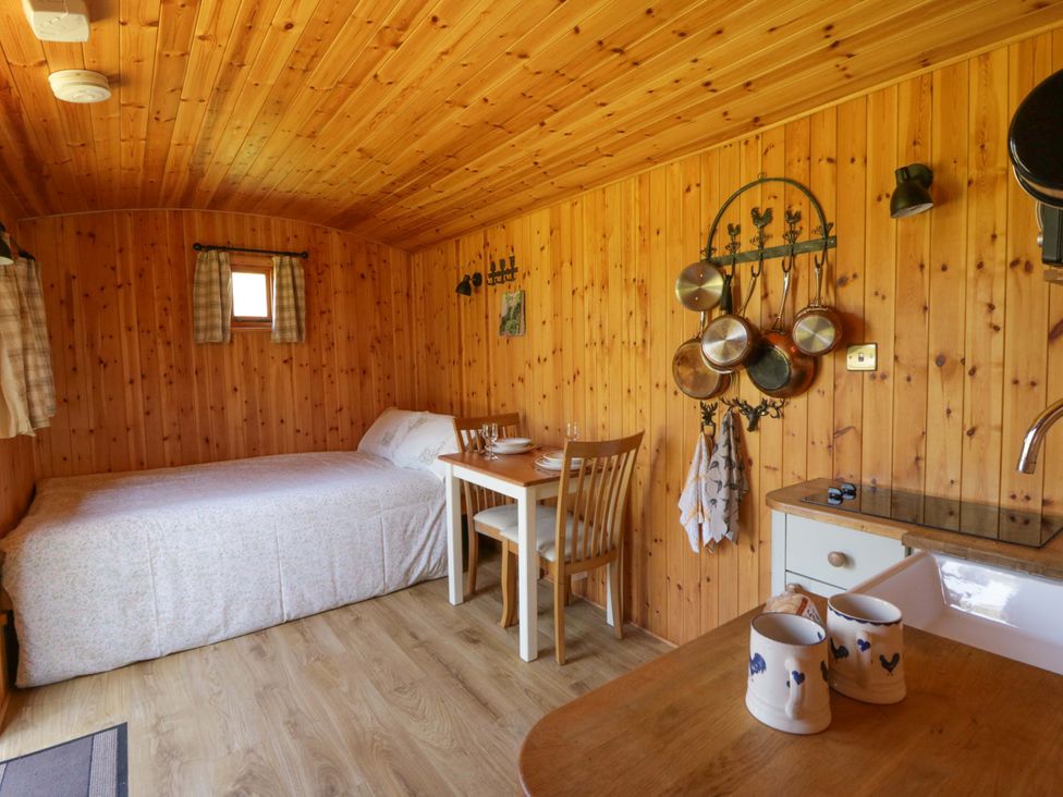 A sleeping area with a bed and table at Bill’s Shepherds Hut near Talgarth