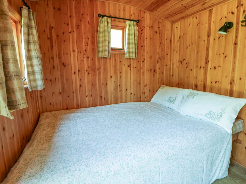 A bedroom with a bed and wooden walls at Bill’s Shepherds Hut near Talgarth
