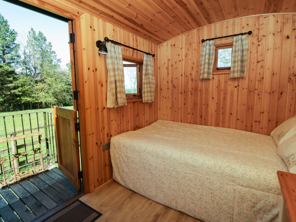 A bedroom with a bed and windows at Bill’s Shepherds Hut near Talgarth