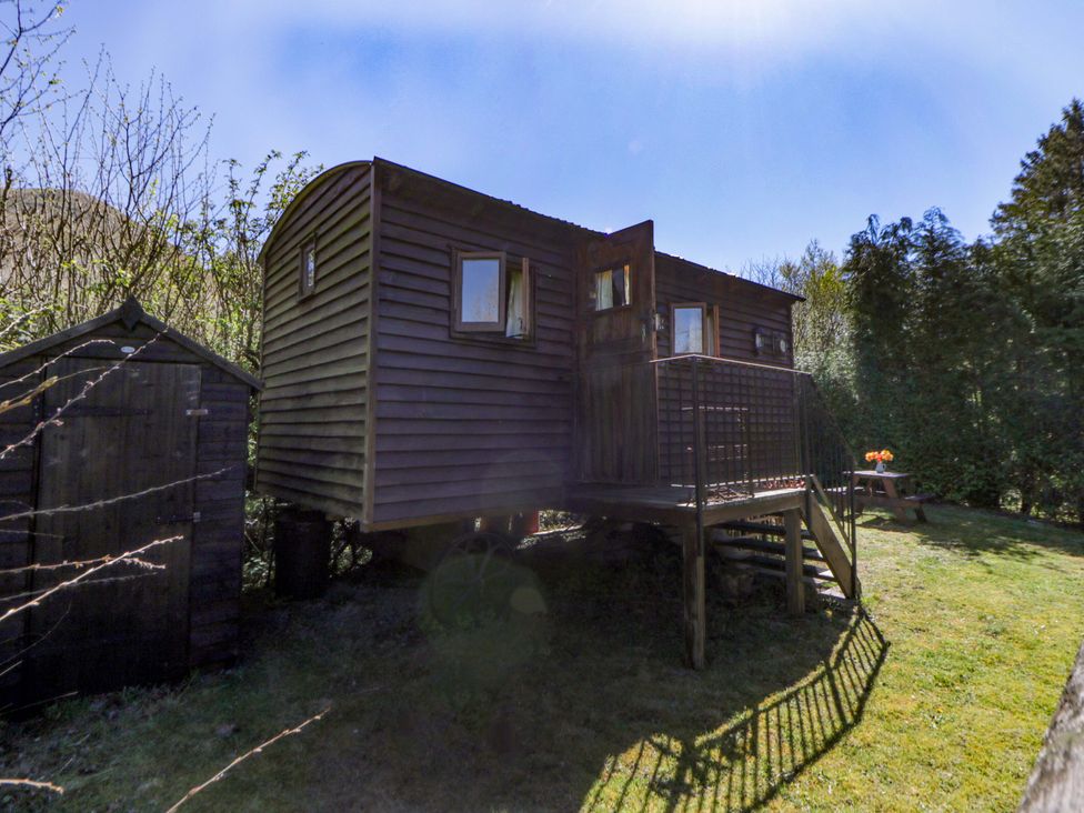A shepherd's hut with steps and wooden shed at Bill’s Shepherds Hut near Talgarth