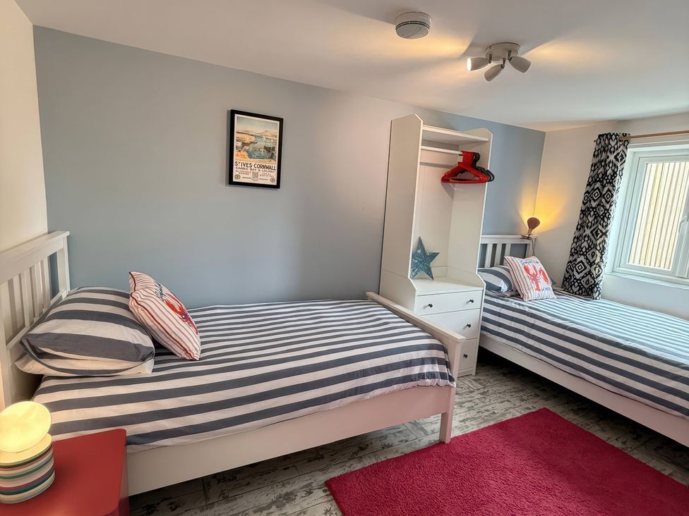 A bedroom with two beds and a shelf at The Packing House in Rosudgeon