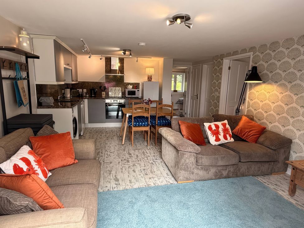 A living room with a sofa and kitchen area at The Packing House in Rosudgeon