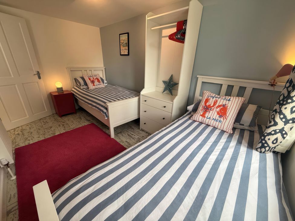A bedroom with two beds and a wardrobe at The Packing House in Rosudgeon