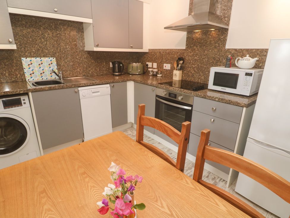 A kitchen with appliances and a dining table at The Packing House in Rosudgeon