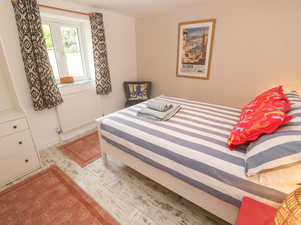 A bedroom with a bed and window at The Packing House in Rosudgeon