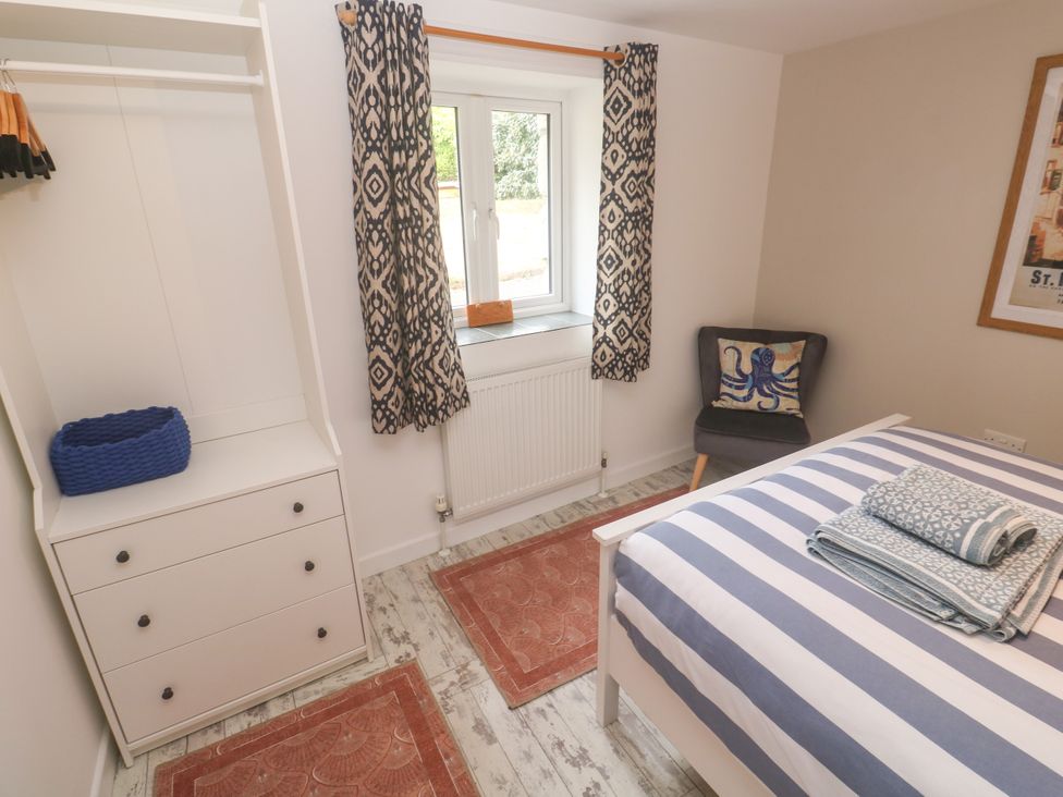 A bedroom with a bed and wardrobe at The Packing House in Rosudgeon