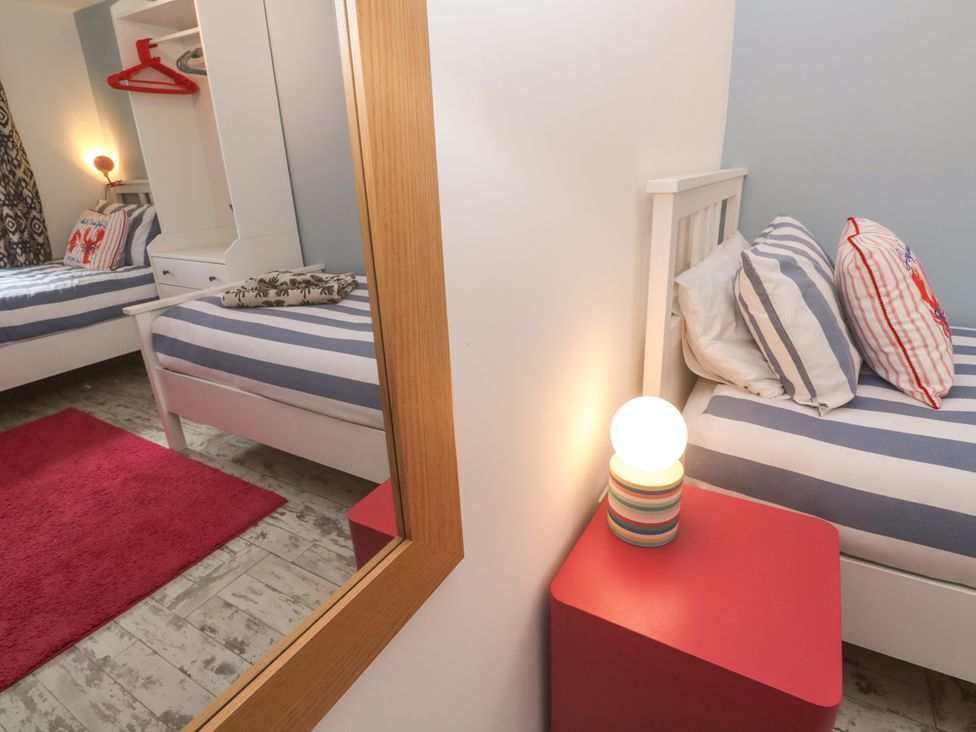 A bedroom with two beds and a wardrobe at The Packing House in Rosudgeon