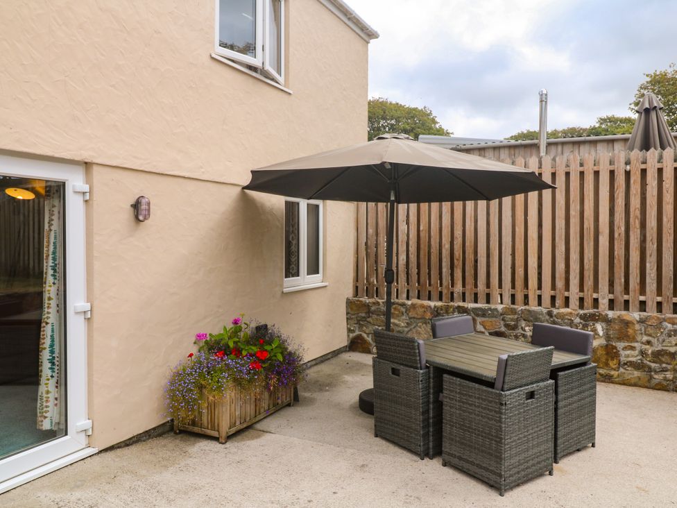A patio area with a table and chairs under an umbrella at The Packing House in Rosudgeon
