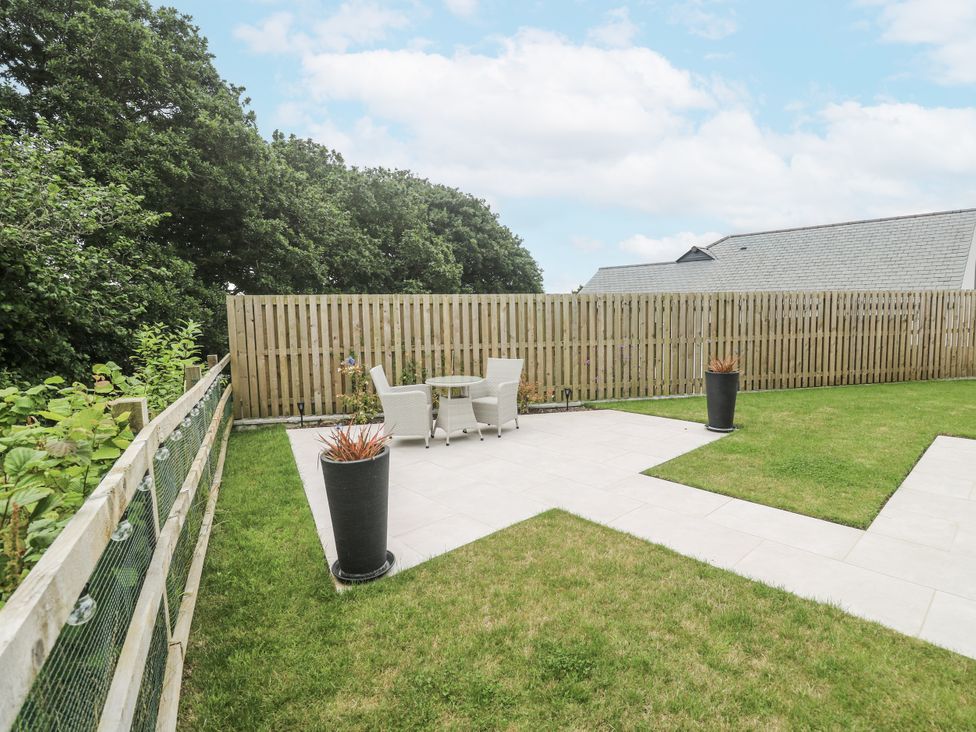 A garden with a table and chairs and planters at Kerrek Lodge Mylor Bridge