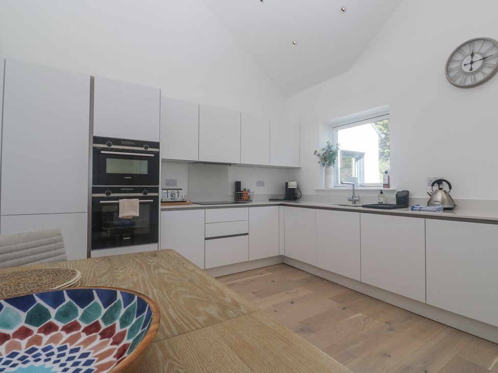 A kitchen with cabinets and appliances at Kerrek Lodge in Mylor Bridge
