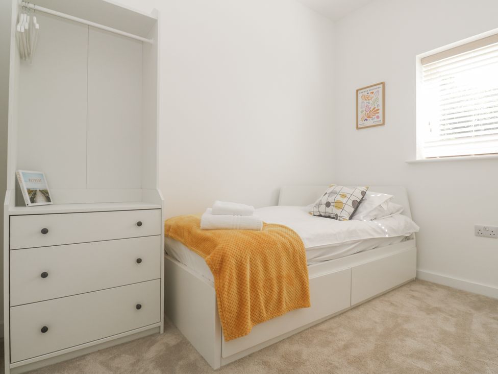 A bedroom with a bed, dresser, and wardrobe at Kerrek Lodge in Mylor Bridge