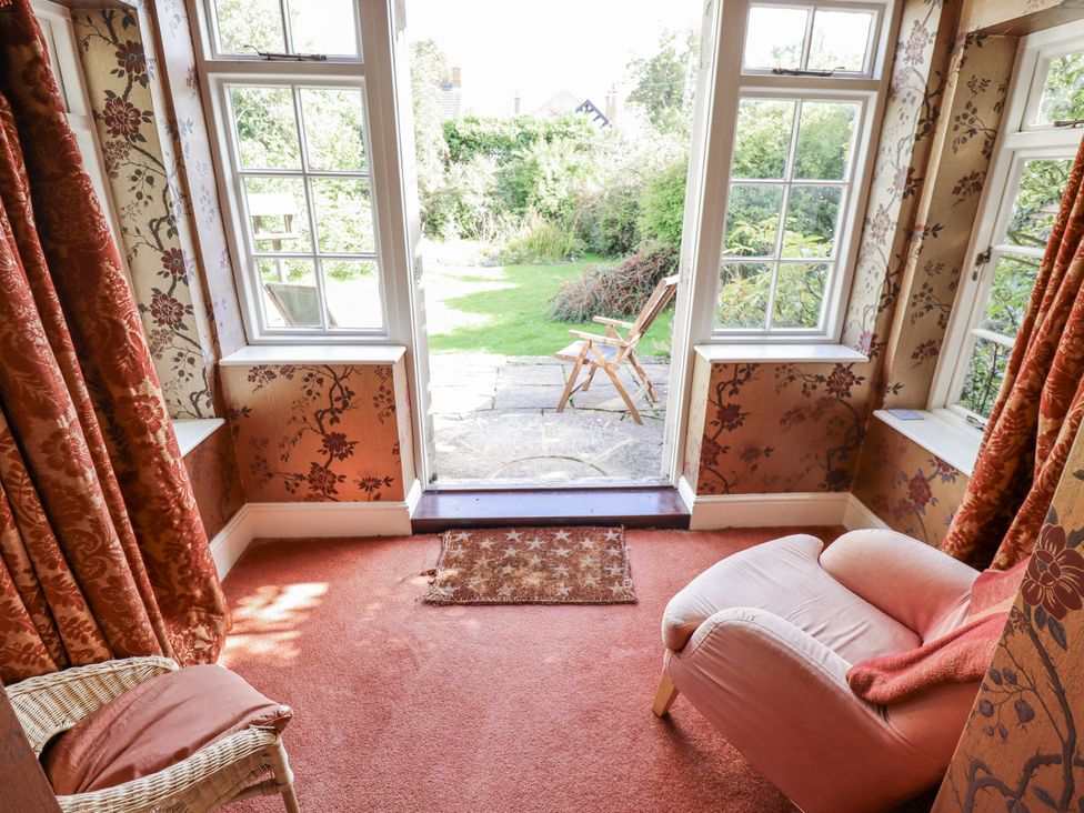 A snug with an armchair and a door to the garden at Holme Farm in Ruskington