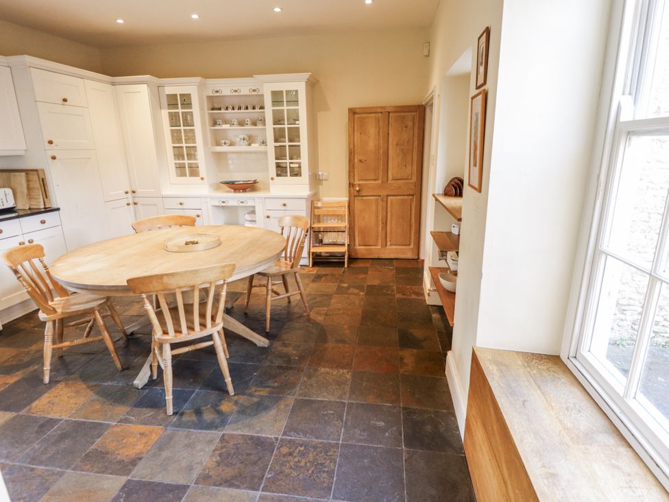 A kitchen with a round table and wooden chairs at Holme Farm in Ruskington