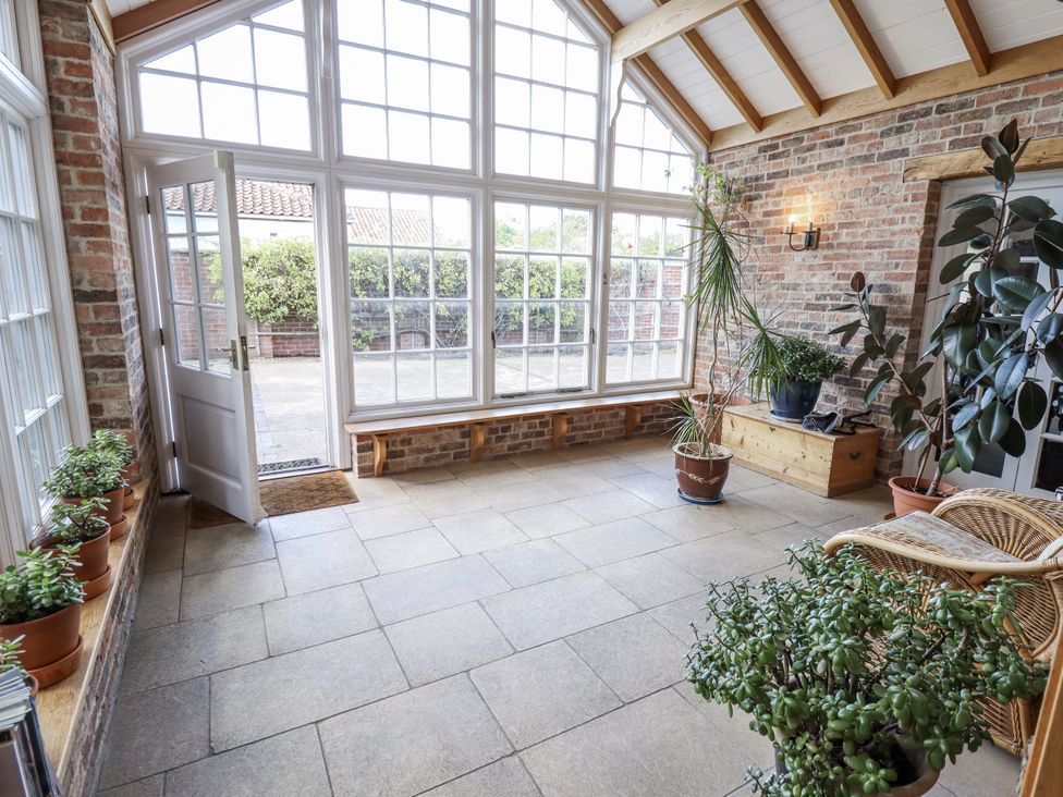 A conservatory with large windows and plants at Holme Farm in Ruskington