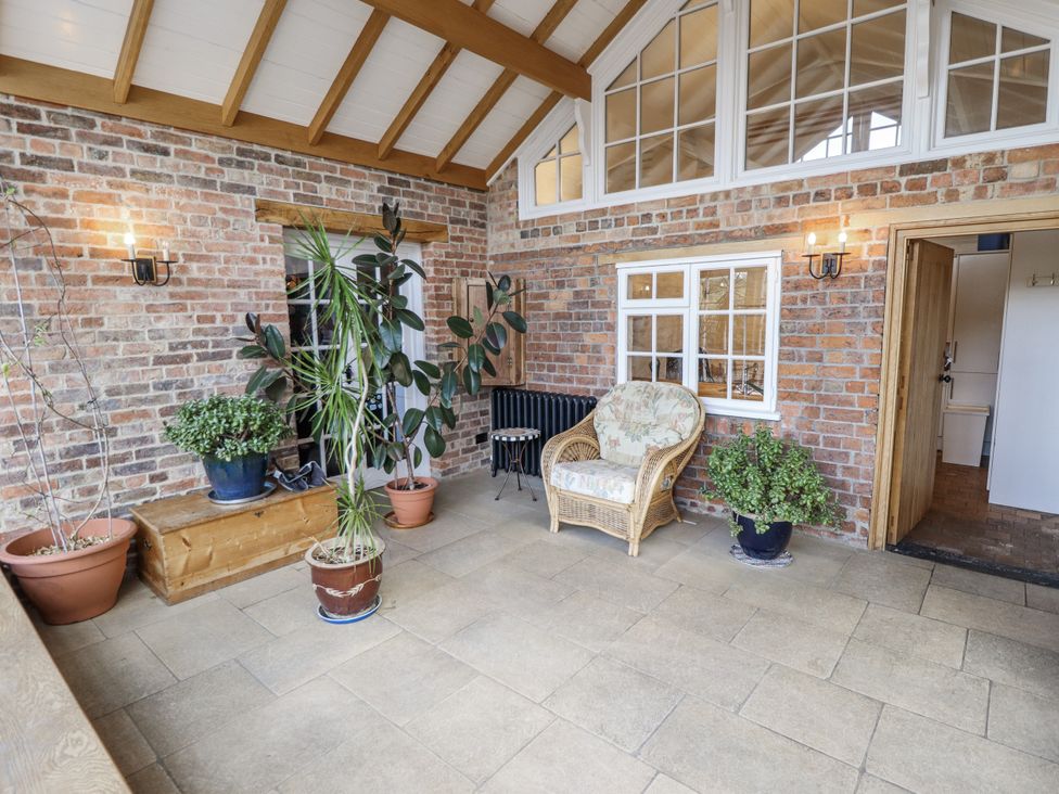 A conservatory with a sofa and plants at Holme Farm in Ruskington