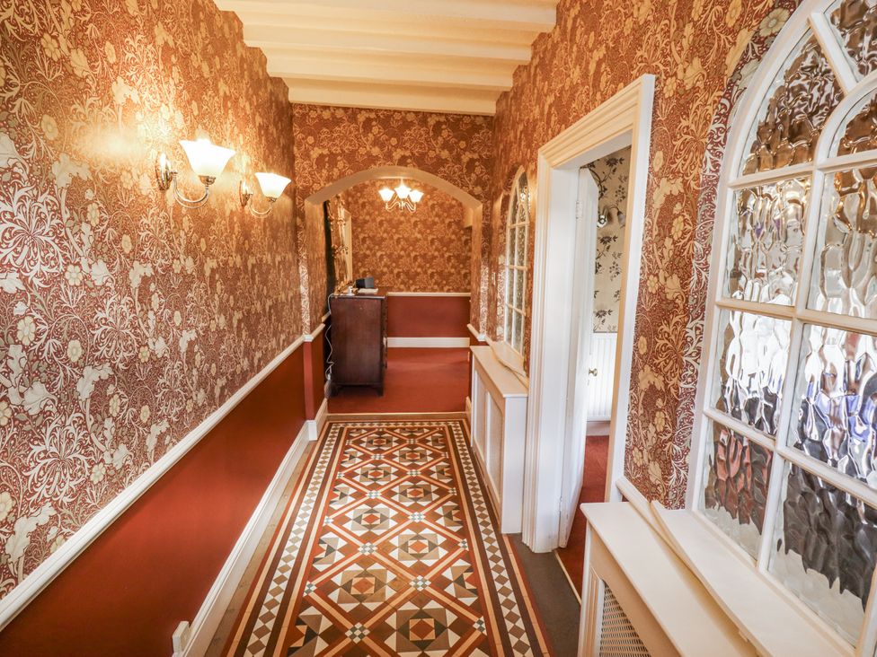 A hallway with decorative wallpaper and patterned flooring at Holme Farm in Ruskington