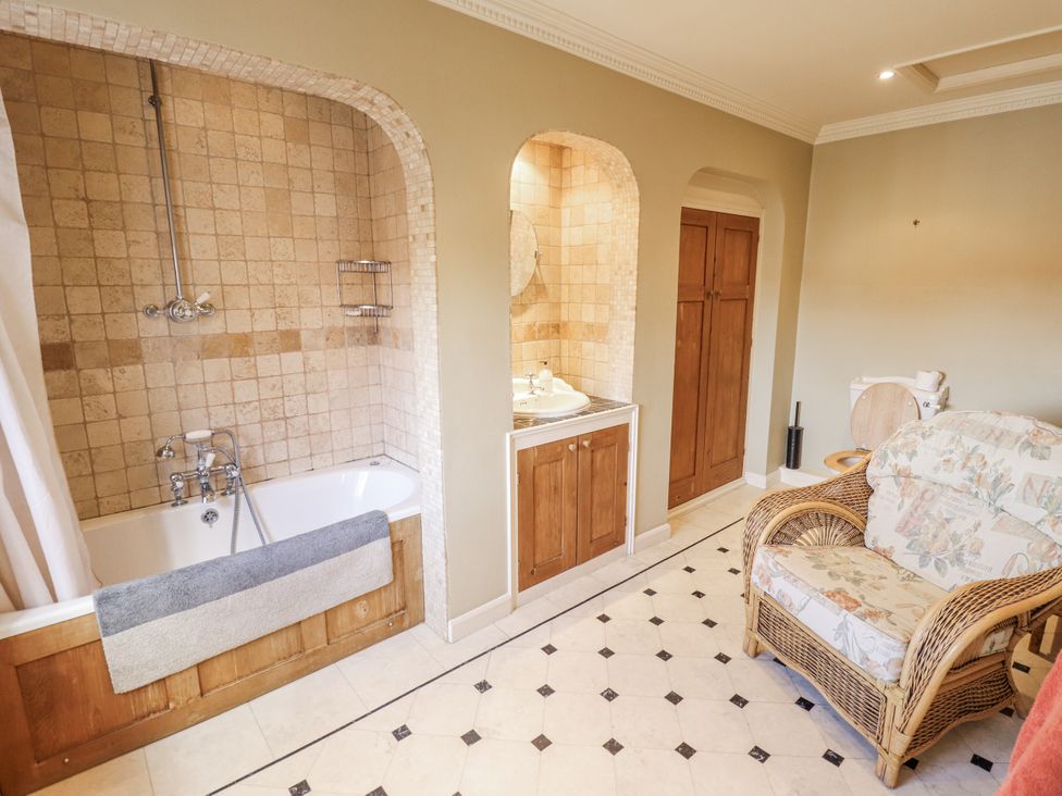 A bathroom with a bathtub and sink at Holme Farm in Ruskington