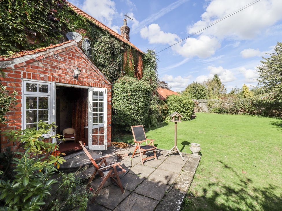 A garden with a brick building and seating area at Holme Farm in Ruskington