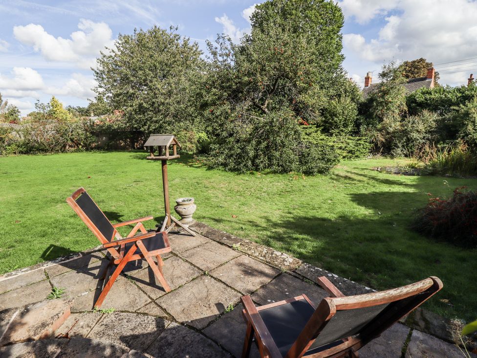 A garden with chairs and a bird feeder at Holme Farm in Ruskington