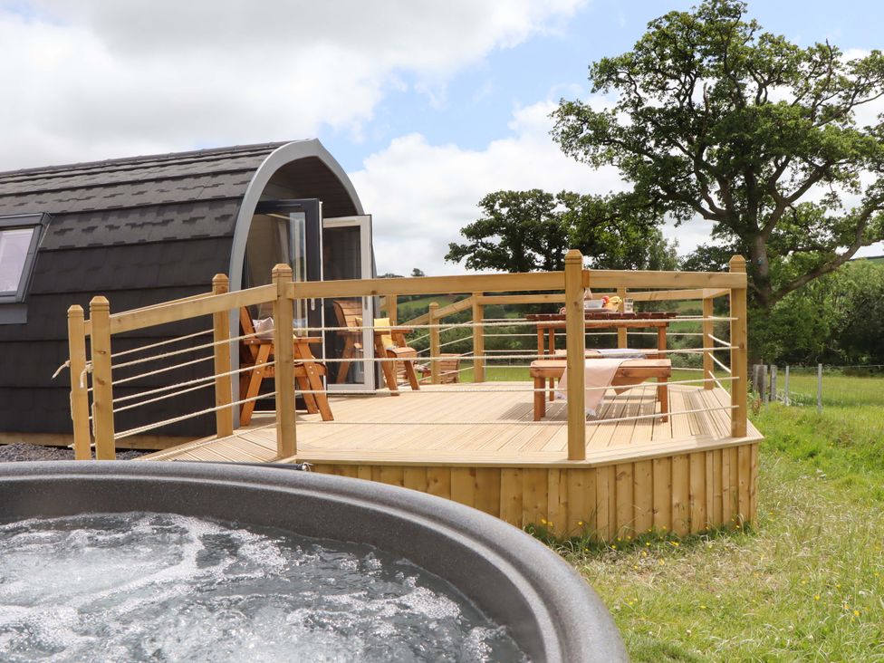 An outdoor area with a deck, hot tub, and seating at Under Oak Pod in Totnes