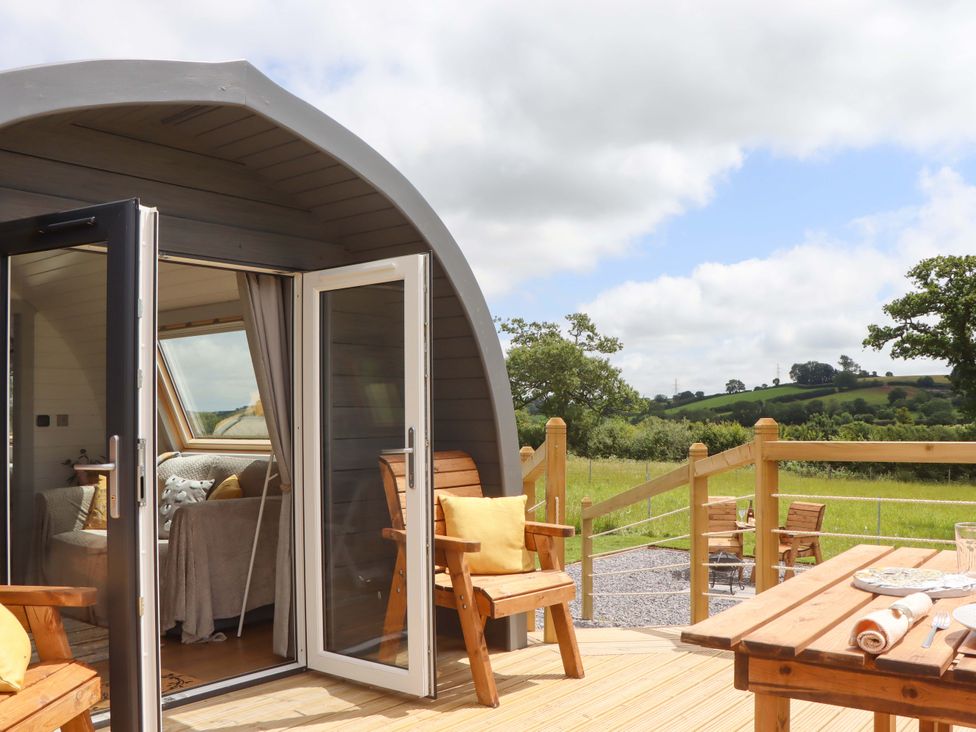 A pod with chairs and a table on a deck at Under Oak Pod in Totnes
