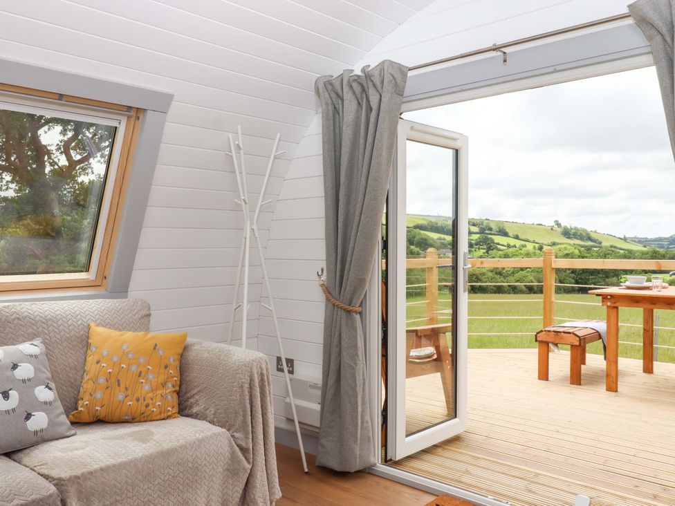 A living room with a sofa and a view of the outside deck at Under Oak Pod in Totnes