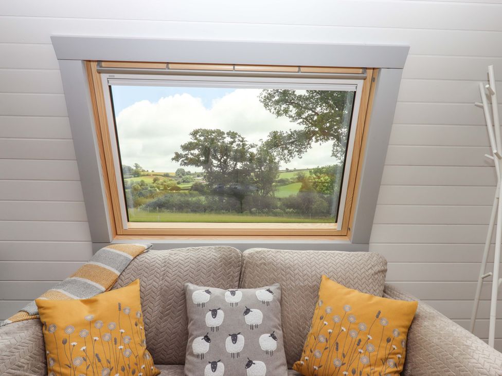 A living room with a window showing the countryside at Under Oak Pod in Totnes