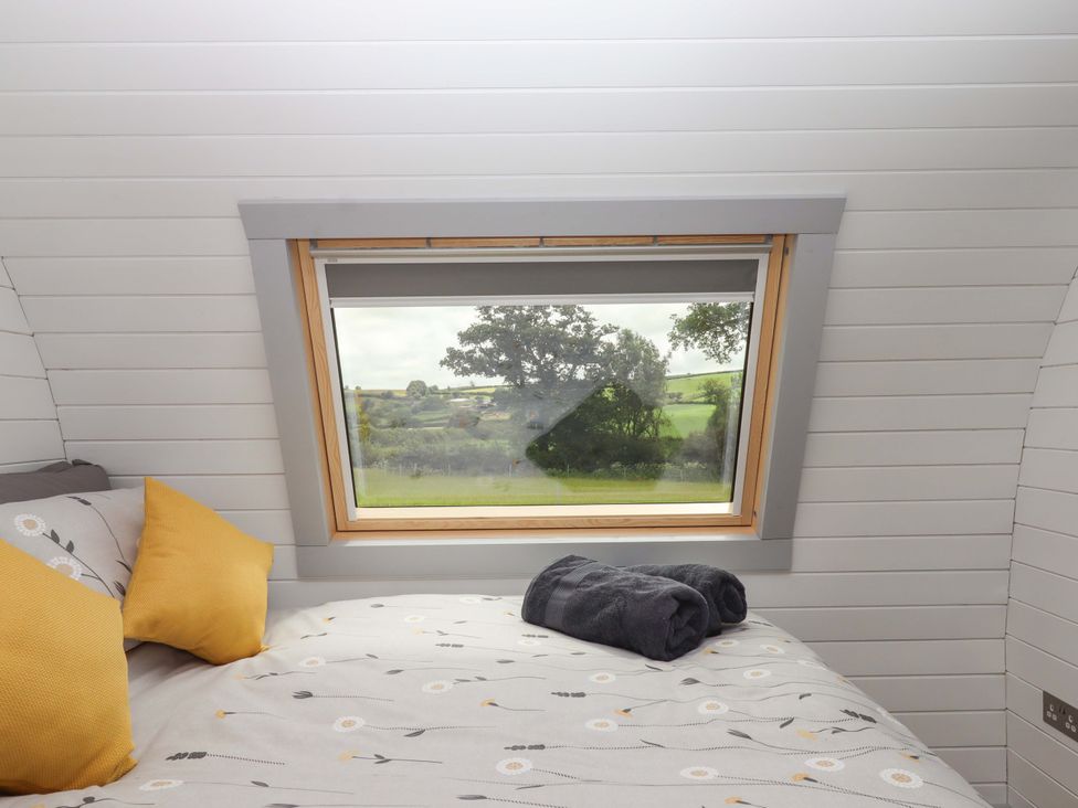 A bedroom with a bed and window at Under Oak Pod in Totnes