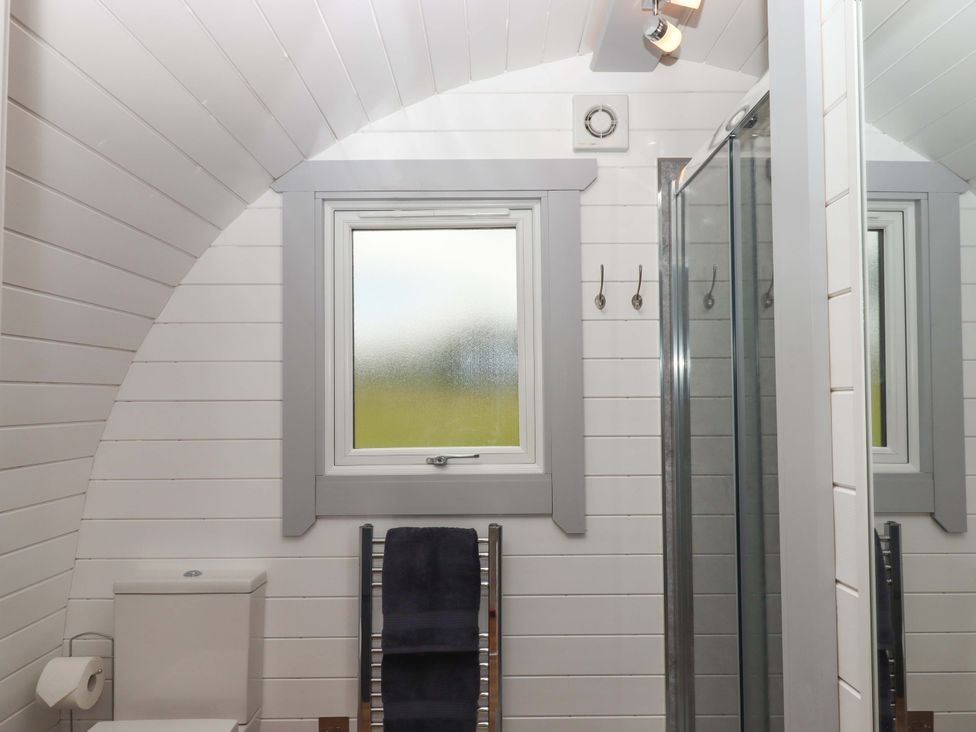 A bathroom with a toilet, towel rack, and shower at Under Oak Pod in Totnes