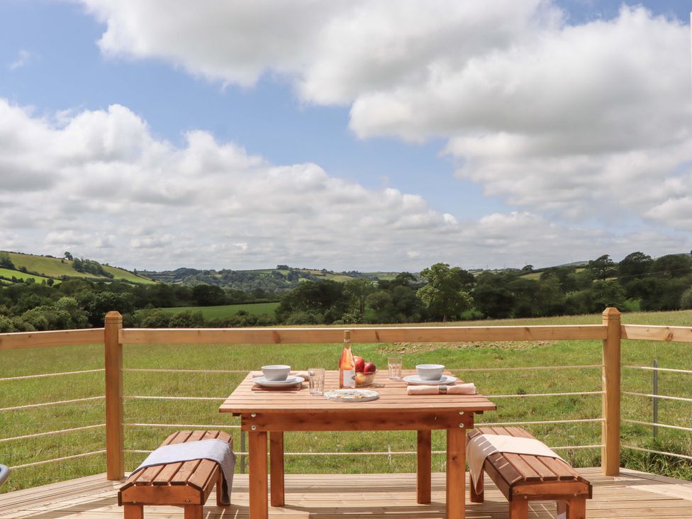 A table with fruit and glass on a deck at Under Oak Pod Totnes