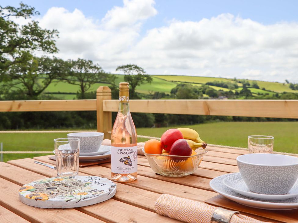 An outdoor dining area with a table set for a meal at Under Oak Pod Totnes