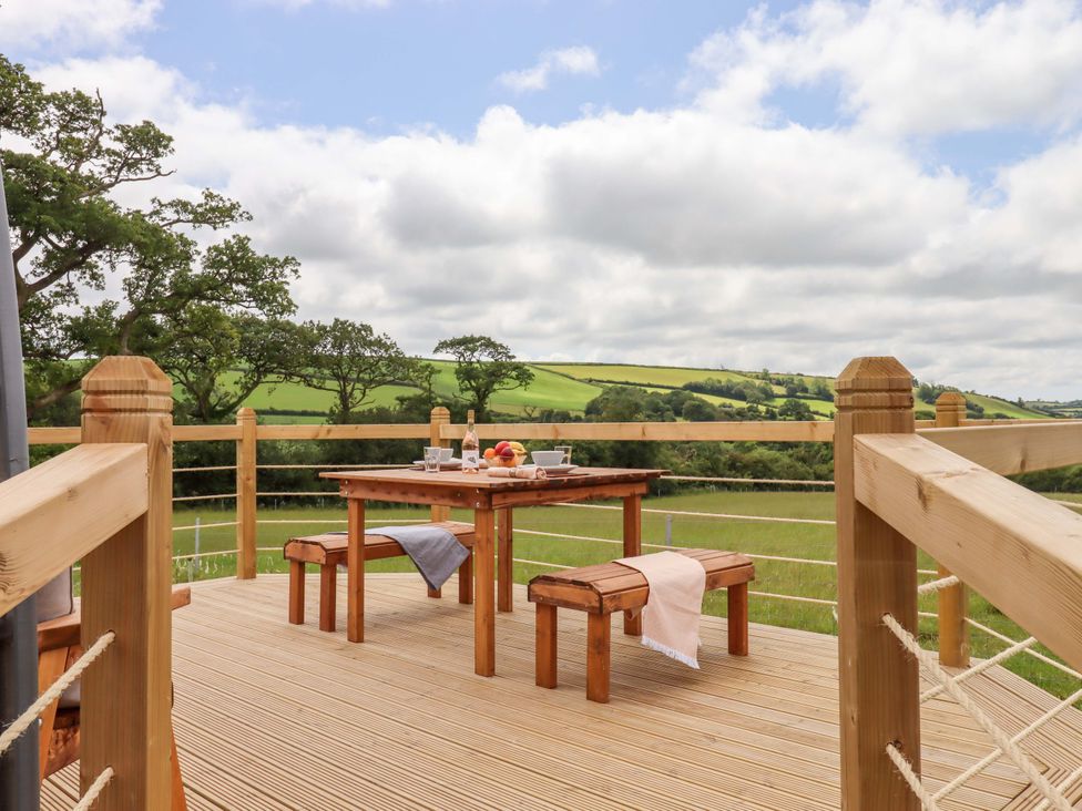 An outdoor dining area with a table and benches at Under Oak Pod in Totnes
