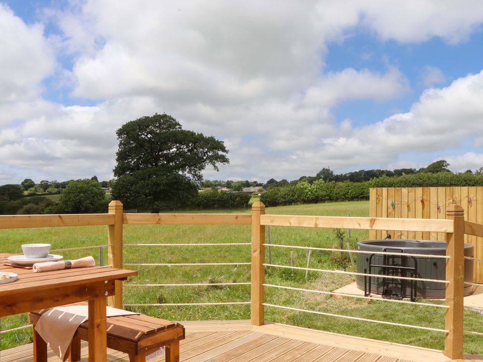 An outdoor area with a table and hot tub at Under Oak Pod in Totnes