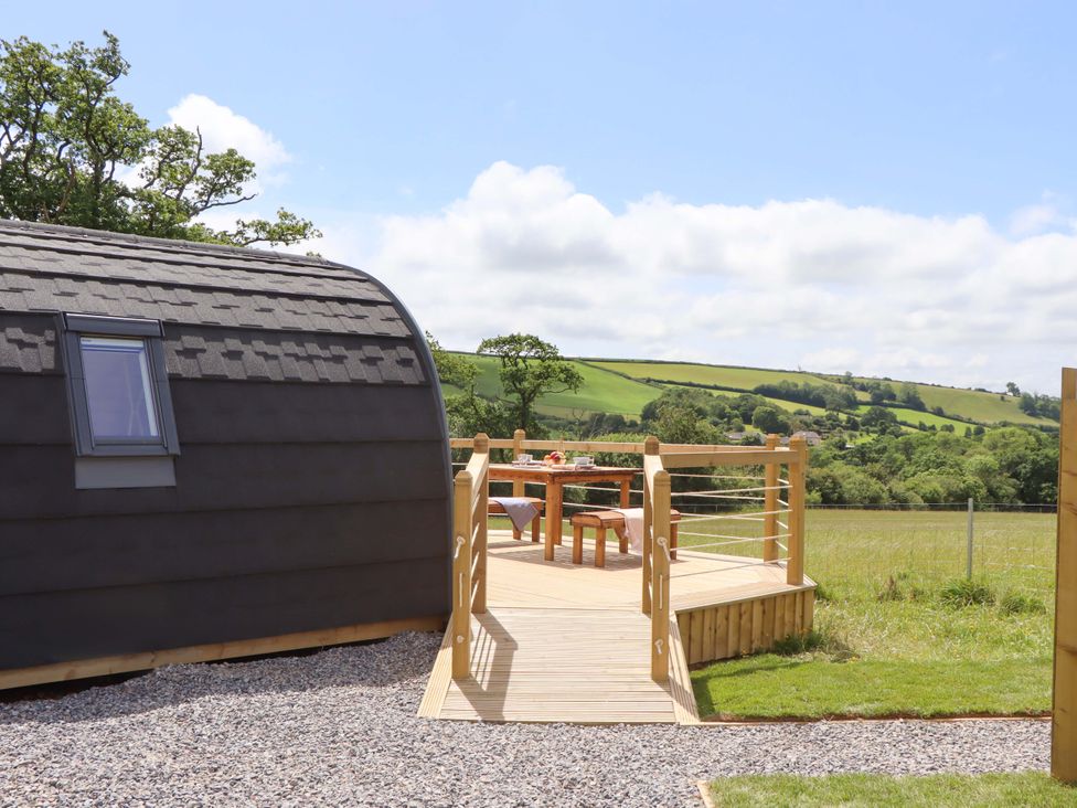 A cabin with a deck and table at Under Oak Pod in Totnes