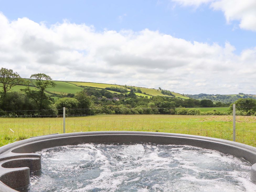A hot tub with a view of hills and fields at Under Oak Pod in Totnes