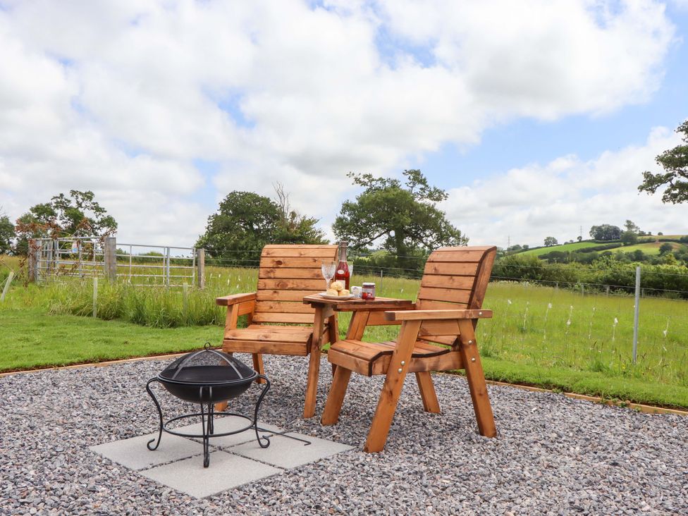 An outdoor seating area with wooden chairs and a fire pit at Under Oak Pod in Totnes