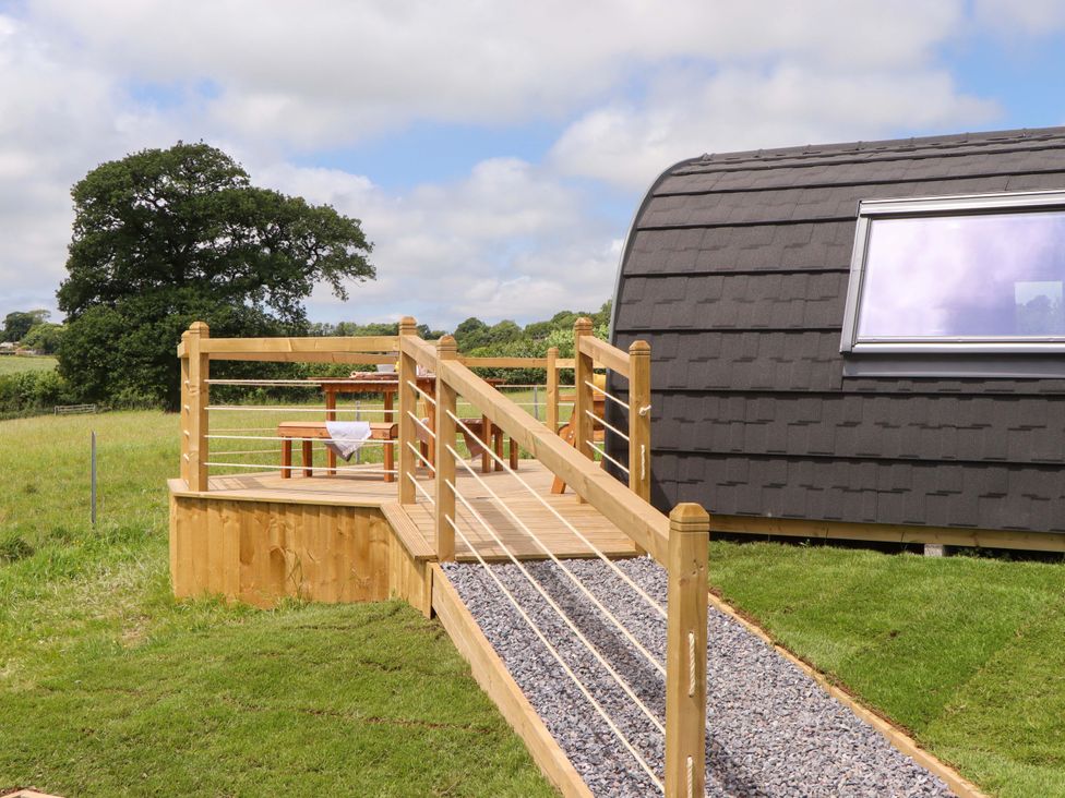 An outdoor area with a wooden deck and table at Under Oak Pod in Totnes