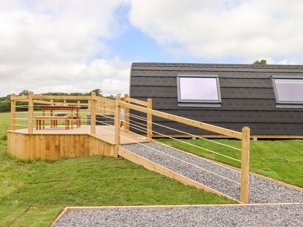 An outdoor area with decking, table, and chairs at Under Oak Pod Totnes