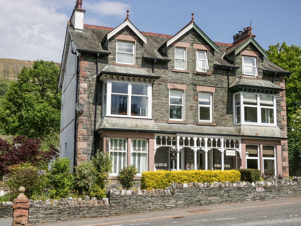 A stone building with multiple windows and a garden in front at Sunnycroft in Keswick