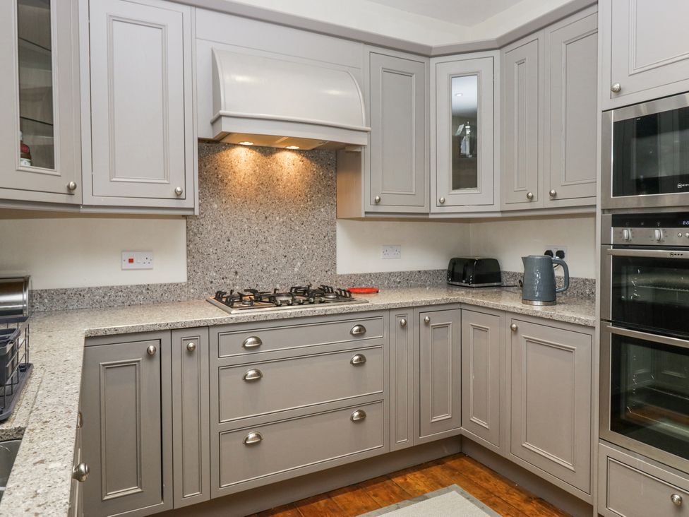 A kitchen with grey cabinets a gas stove a toaster and an electric kettle at Sunnycroft in Keswick