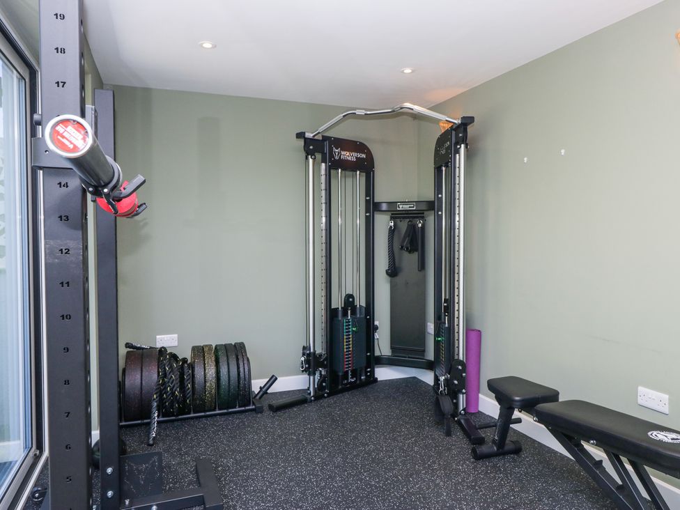 A home gym with weight plates, a cable machine, a bench, and a foam roller at Sunnycroft in Keswick