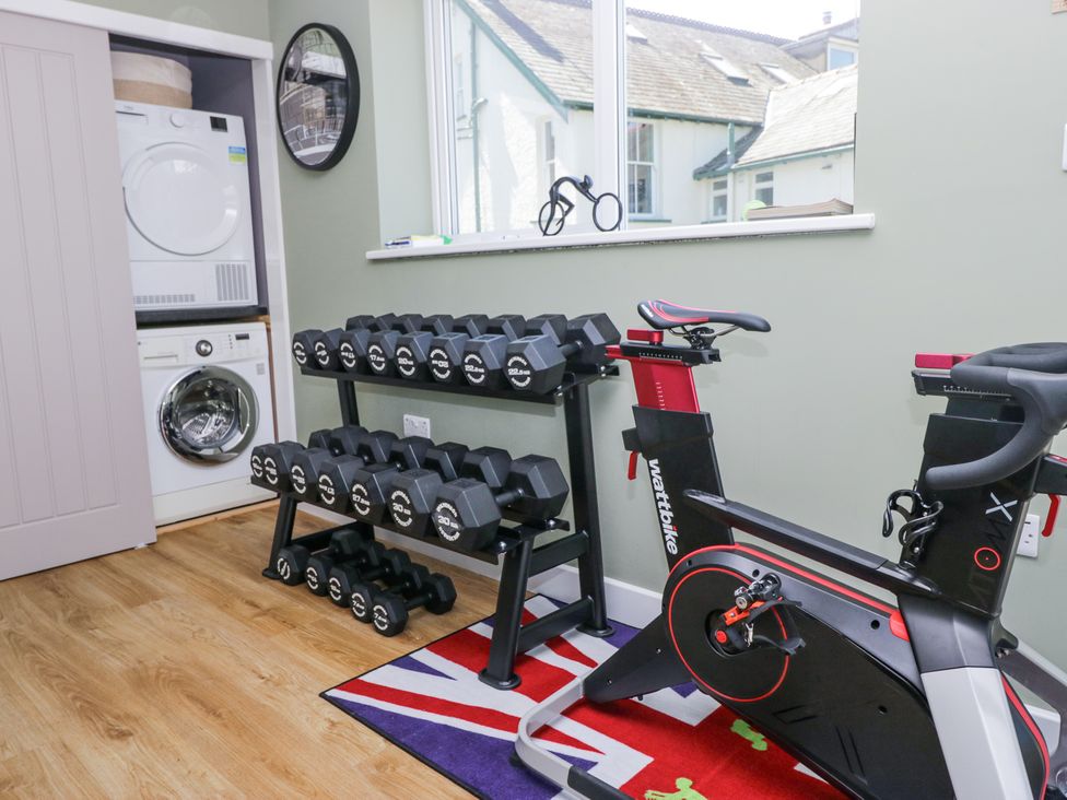 A home gym with a stationary bike, a rack of dumbbells, and a stacked washer and dryer unit