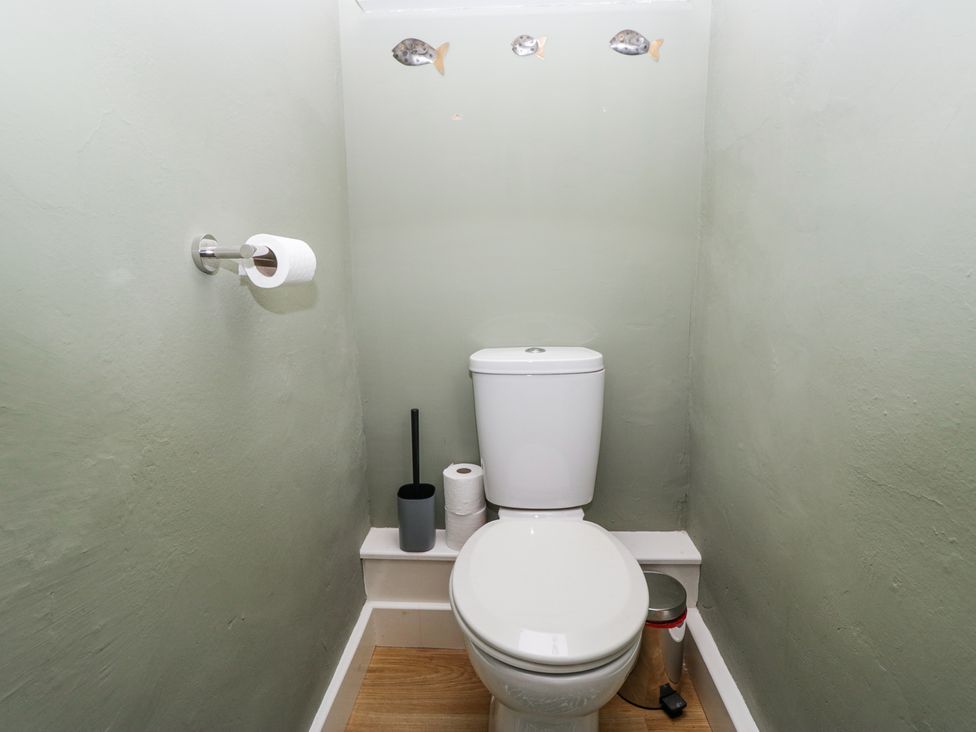 A small bathroom with a toilet a toilet brush a trash can and a toilet paper holder with a roll at Sunnycroft in Keswick