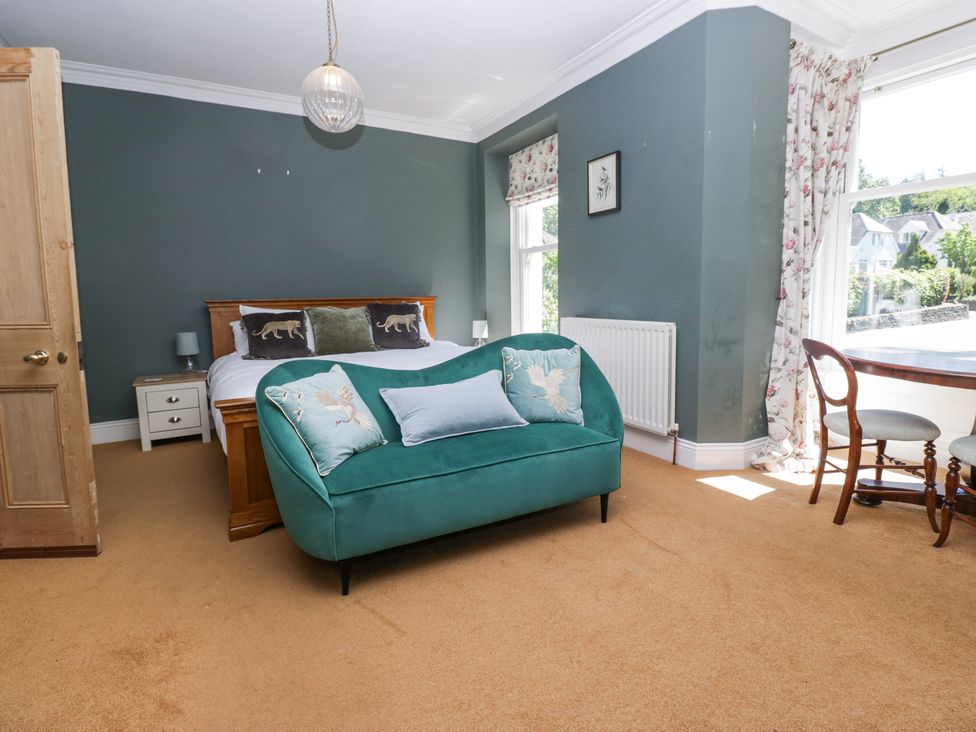 A bedroom with a double bed green sofa wooden table and chairs at Sunnycroft in Keswick