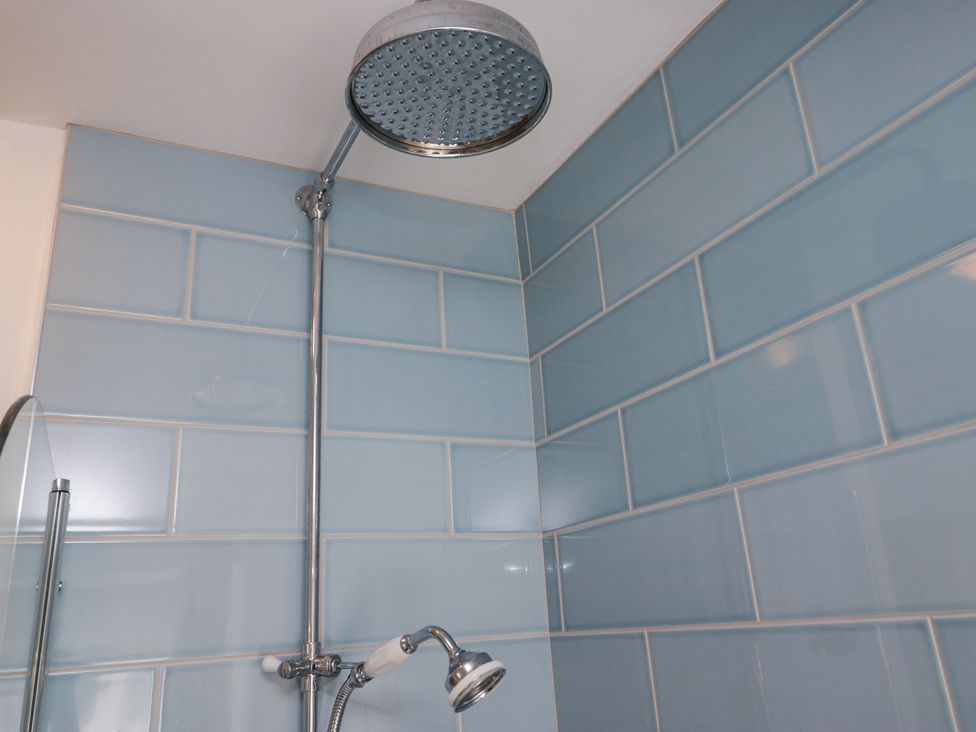 A shower area with blue tiled walls and a large round showerhead at Sunnycroft in Keswick