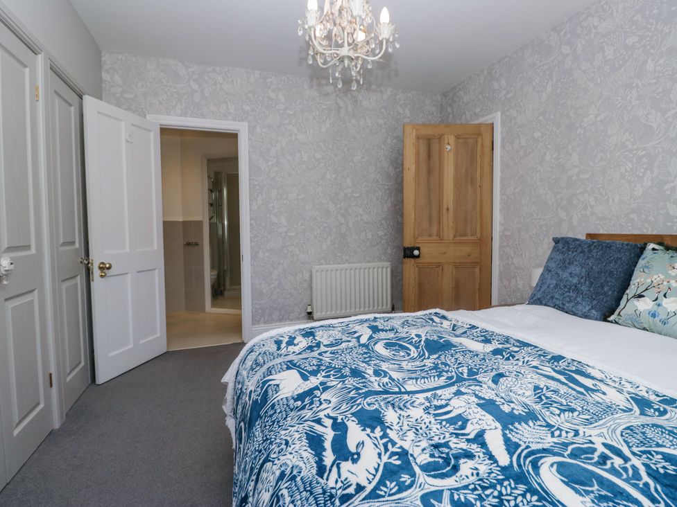 A bedroom with a bed covered in blue and white bedding near wooden and white doors at Sunnycroft in Keswick
