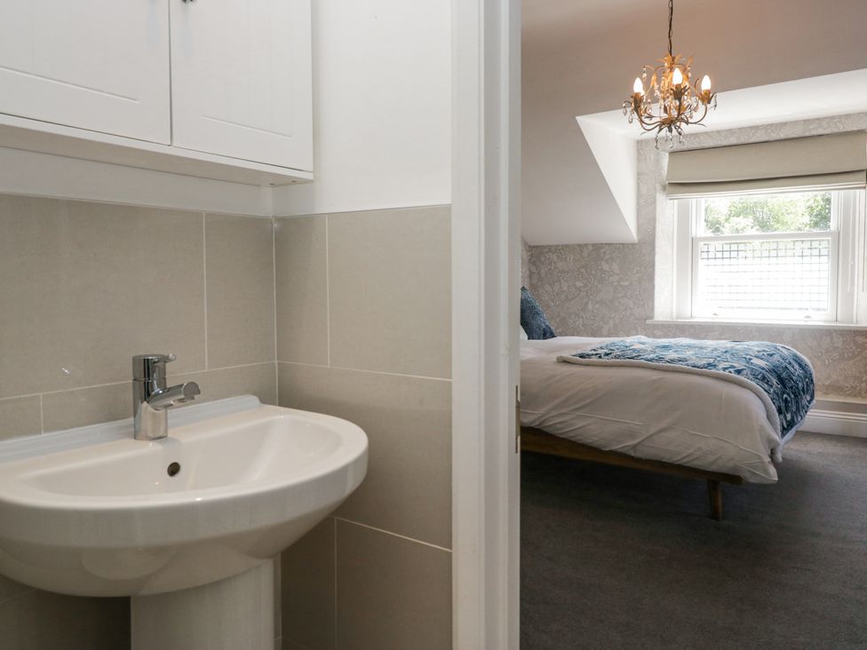 A bathroom sink with faucet next to a bedroom with a bed and window at Sunnycroft in Keswick
