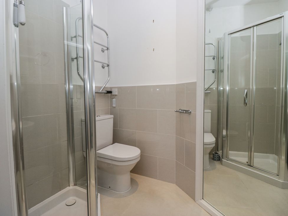 A bathroom with a toilet a glass shower enclosure and a towel rail at Sunnycroft in Keswick